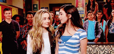 Two Girls Standing Next To Each Other In Front Of A Sign That Says " Head " GIF