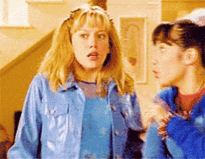 Two Girls Standing, One In Blue Jacket GIF