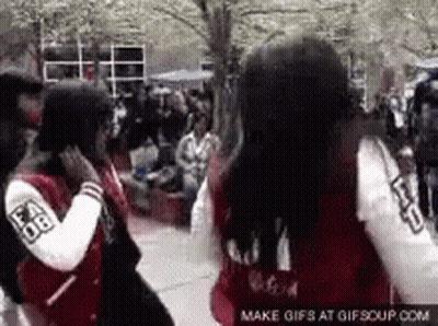Two Girls Wearing Varsity Jackets Are Standing Next To Each Other On A Sidewalk . GIF