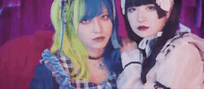 Two Girls With Blue And Green Hair On Red Couch GIF