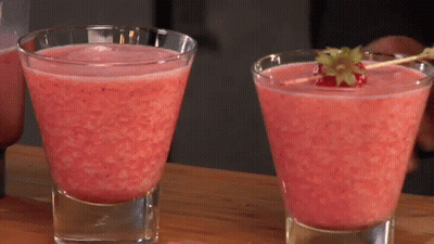Two Glasses Of Pink Liquid With A Strawberry On A Stick GIF