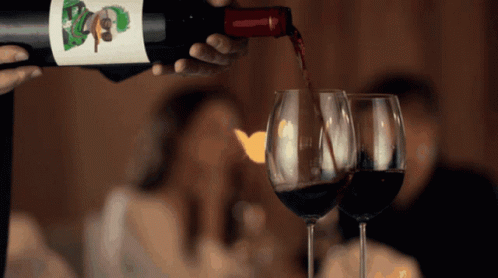 Two Glasses Of Wine Are Being Poured From A Bottle With A Label That Says ' Boys ' GIF