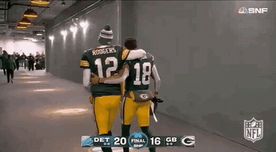 Two Green Bay Packers Players Are Hugging Each Other While Walking Down A Hallway . GIF