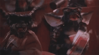 Two Gremlins Standing On Red Background GIF
