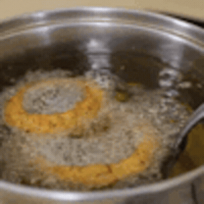 Two Hamburger Patties Cooking In Oil With Fork GIF
