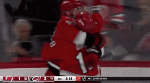 Two Hockey Players Are Hugging Each Other In Front Of A Scoreboard That Says Nhl Scoreboard On It GIF