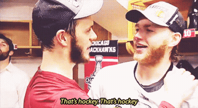 Two Hockey Players Are Hugging In Front Of A Chicago Blackhawks Sign GIF