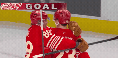 Two Hockey Players Are Hugging In Front Of A Sign That Says Goal GIF