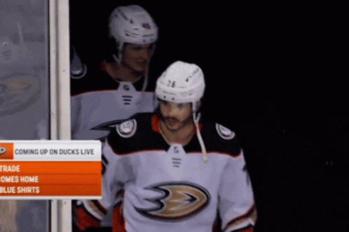 Two Hockey Players Are Standing In Front Of A Sign Which Says Coming Up On Ducks Live GIF