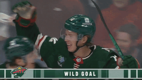 Two Hockey Players Celebrate A Wild Goal With A Banner Behind Them GIF