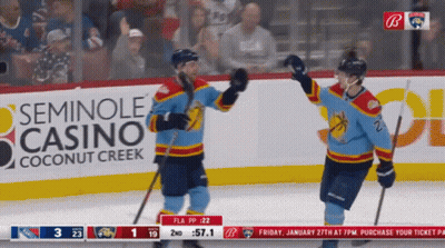 Two Hockey Players Celebrating Goal In Front Of Seminole Casino Ad GIF
