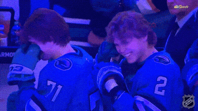 Two Hockey Players Wearing Blue Jerseys With The Number 71 And 2 On Them GIF