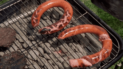Two Horseshoe Shaped Sausages Are Cooking On A Grill Outside GIF