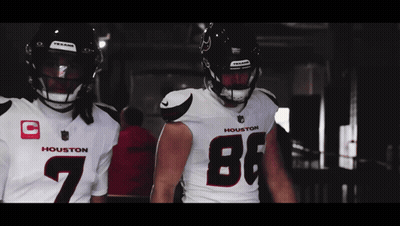 Two Houston Football Players Are Standing Next To Each Other In A Dark Room GIF