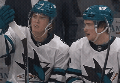 Two Ice Hockey Players Wearing Sap Helmets Are Sitting Next To Each Other GIF