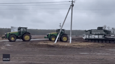 Two John Deere Tractors Parked Next To Each Other GIF