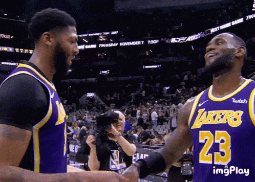 Two Lakers Basketball Players Shake Hands In Front Of A Crowd GIF
