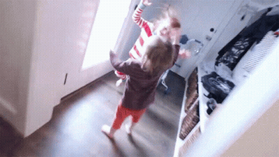 Two Little Girls Are Dancing In A Hallway In Front Of A Door . GIF