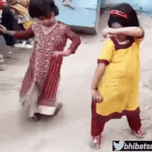 Two Little Girls Are Dancing On A Street And One Of Them Is Wearing A Yellow Shirt . GIF