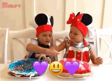 Two Little Girls Are Sitting At A Table With Plates Of Food . One Of The Girls Is Wearing A Mickey Mouse Hat . GIF