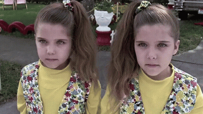 Two Little Girls Are Standing Next To Each Other On The Sidewalk GIF