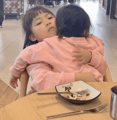 Two Little Girls Hugging With Plate Of Food GIF