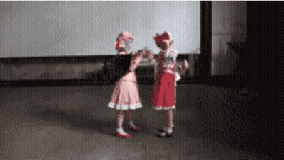 Two Little Girls In Pink And Red Dresses Are Dancing Together On A Stage . GIF