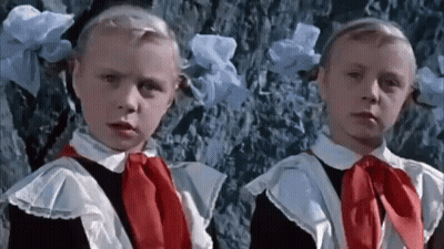Two Little Girls In School Uniforms Are Standing Next To Each Other . GIF