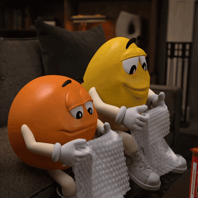 Two M&Ms Sitting On Couch With Bubble Wrap GIF