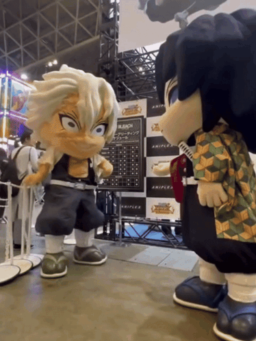 Two Mascots Are Standing Next To Each Other In Front Of Bleach Posters GIF