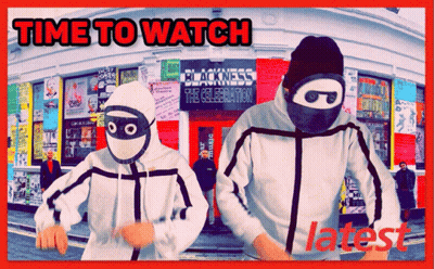 Two Masked People Are Standing In Front Of The Blackness The Celebration GIF