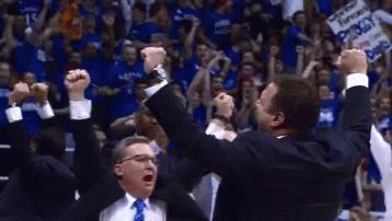 Two Men Are Celebrating With Their Arms In The Air In Front Of A Crowd With A Sign That Says ' Kansas ' On It GIF