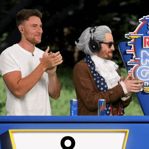 Two Men Are Clapping In Front Of A Sign That Says Red Bull On It GIF