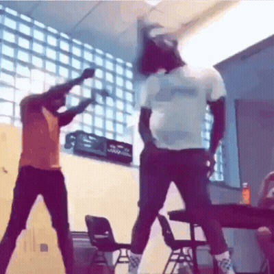 Two Men Are Dancing In A Classroom With Chairs And A Crate In The Background . GIF