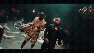 Two Men Are Dancing In A Dark Room With A Chandelier Hanging From The Ceiling . GIF