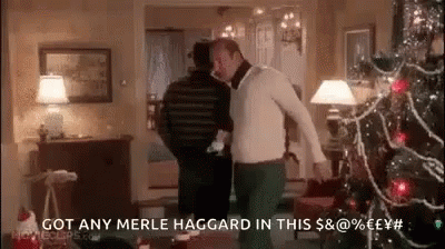 Two Men Are Dancing In A Living Room With A Christmas Tree . GIF