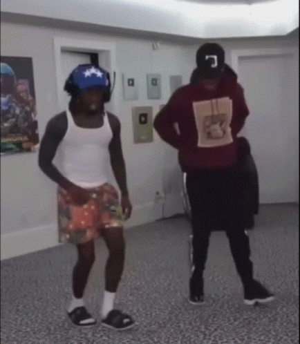 Two Men Are Dancing In A Room And One Of Them Is Wearing A Red Hoodie With The Letter C On It GIF