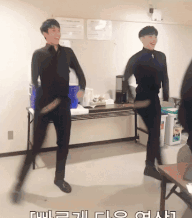 Two Men Are Dancing In A Room With Korean Writing On The Wall GIF