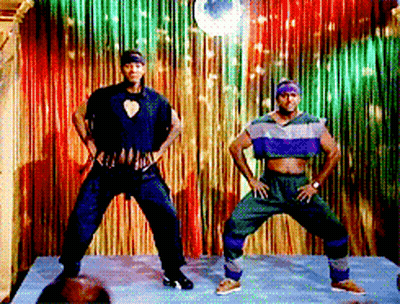 Two Men Are Dancing In Front Of A Colorful Curtain GIF