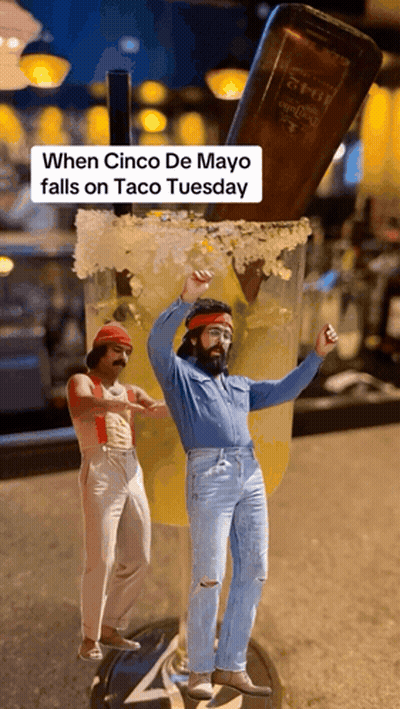 Two Men Are Dancing In Front Of A Giant Margarita Glass With A Bottle Of Tequila In The Background GIF