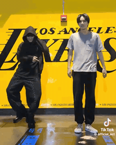 Two Men Are Dancing In Front Of A Los Angeles Lakers Poster GIF