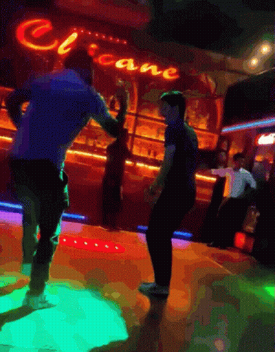 Two Men Are Dancing In Front Of A Neon Sign That Says Cocaine GIF