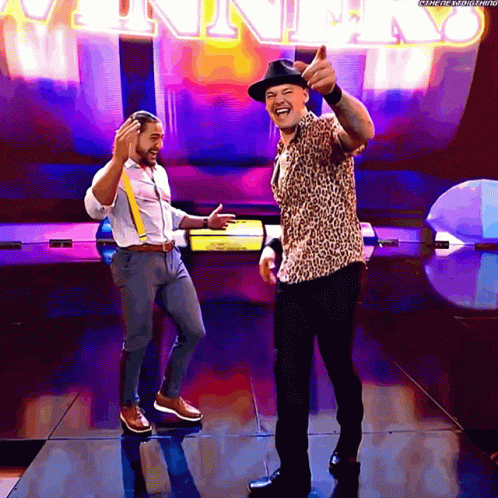 Two Men Are Dancing In Front Of A Sign That Says ' Winner ' GIF