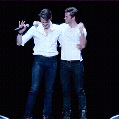 Two Men Are Dancing On A Stage Holding Hands GIF