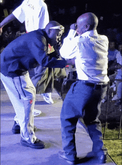 Two Men Are Dancing On A Stage With One Wearing A Shirt That Says ' Oakland ' On It GIF