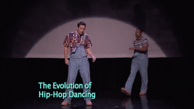 Two Men Are Dancing On A Stage With The Words " The Evolution Of Hip-Hop Dancing " Below Them GIF