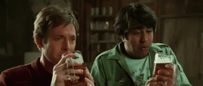 Two Men Are Drinking Beer Together In A Bar And Talking To Each Other . GIF