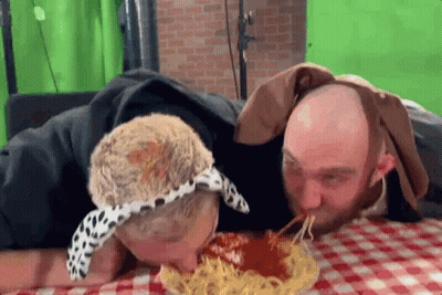 Two Men Are Eating Spaghetti Together On A Checkered Table Cloth . GIF