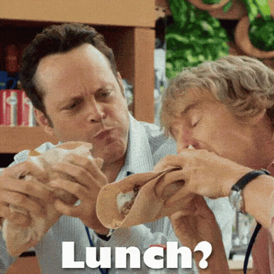 Two Men Are Eating Tacos Together And The Word Lunch Is Above Them . GIF
