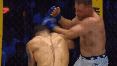 two men are fighting in a boxing ring and one of them has a tattoo on his back .